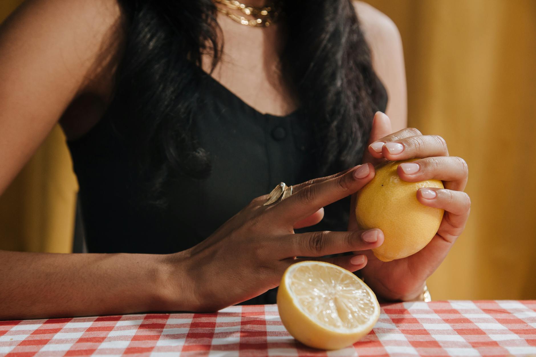 Femme tenant un citron frais à une table à manger, symbole de la vitalité et du plaisir naturel