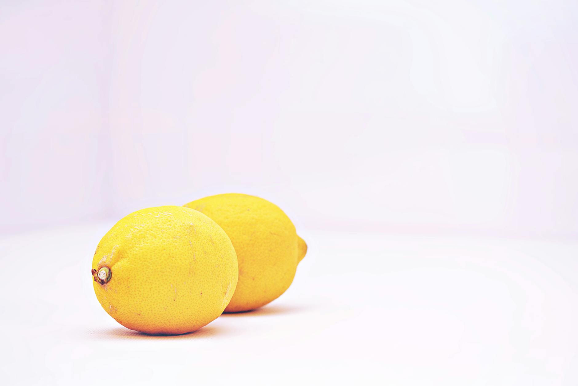 Deux citrons vibrants sur fond blanc minimaliste, symbole de fraîcheur et de nouvelle intimité