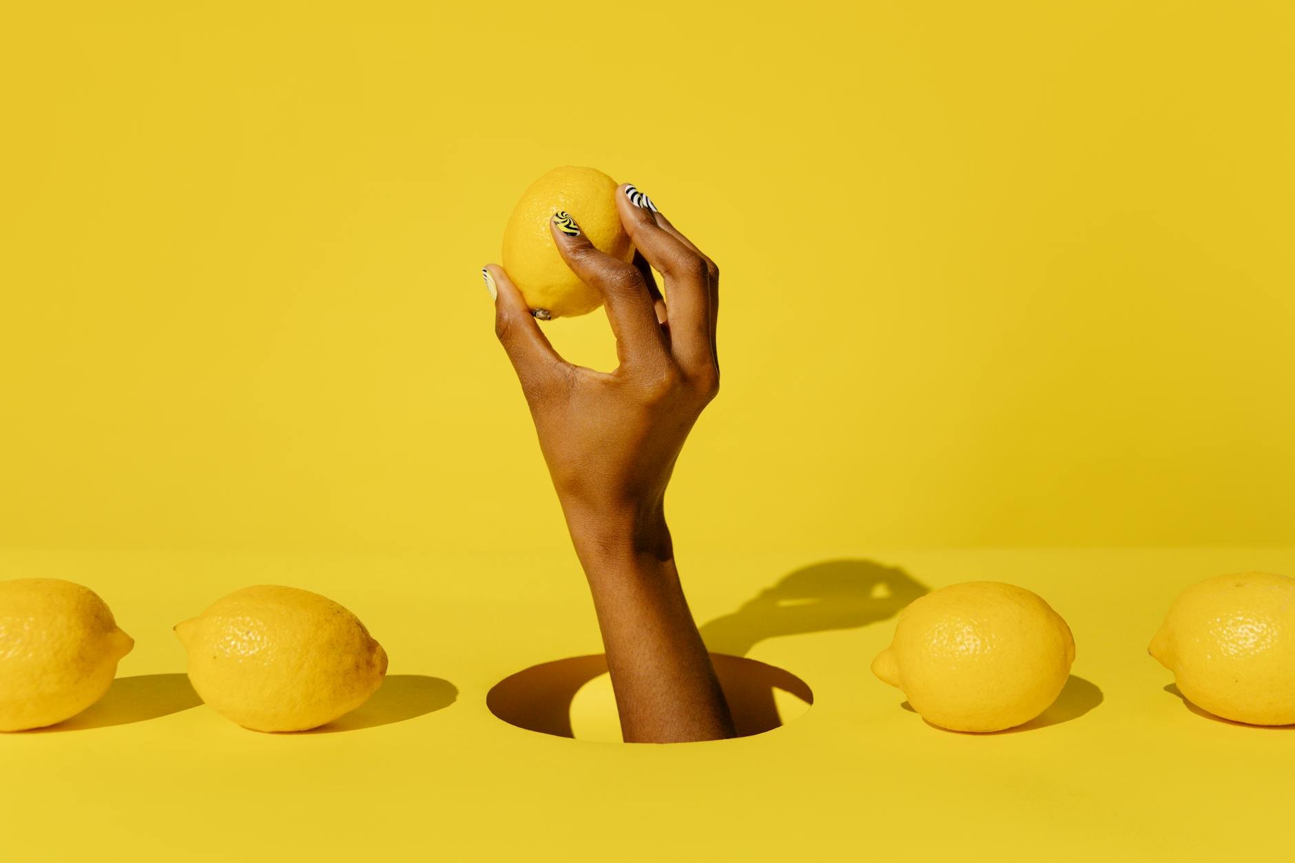 Une main tenant un citron frais sur un fond jaune vibrant, évoquant la fraîcheur et la curiosité