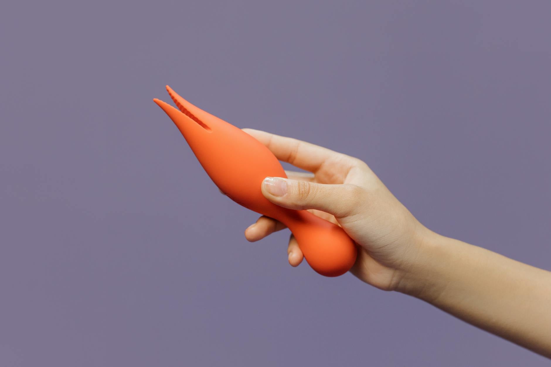 Gros plan d'une main tenant un vibromasseur citron contre un fond violet minimaliste, mettant en avant la sensualité moderne.