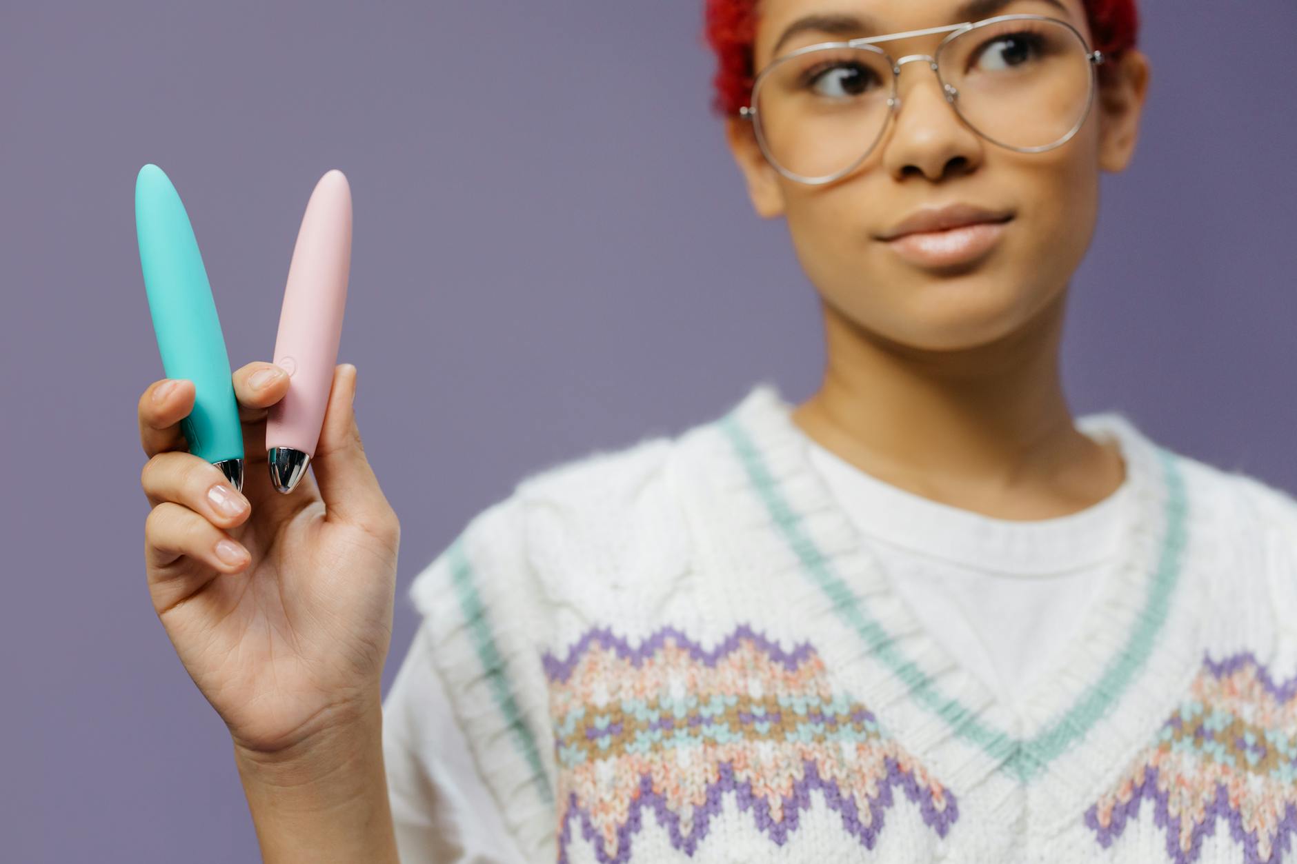 Un vibromasseur bleu en silicone tenu à la main sur un fond violet, promouvant l'amour de soi et la sexualité