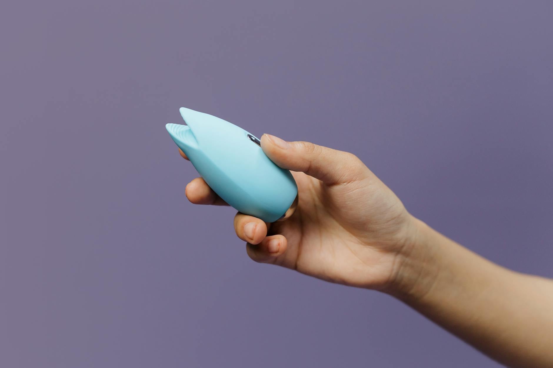 Femme tenant des vibromasseurs silicone bleu et rose d'une manière contemplative