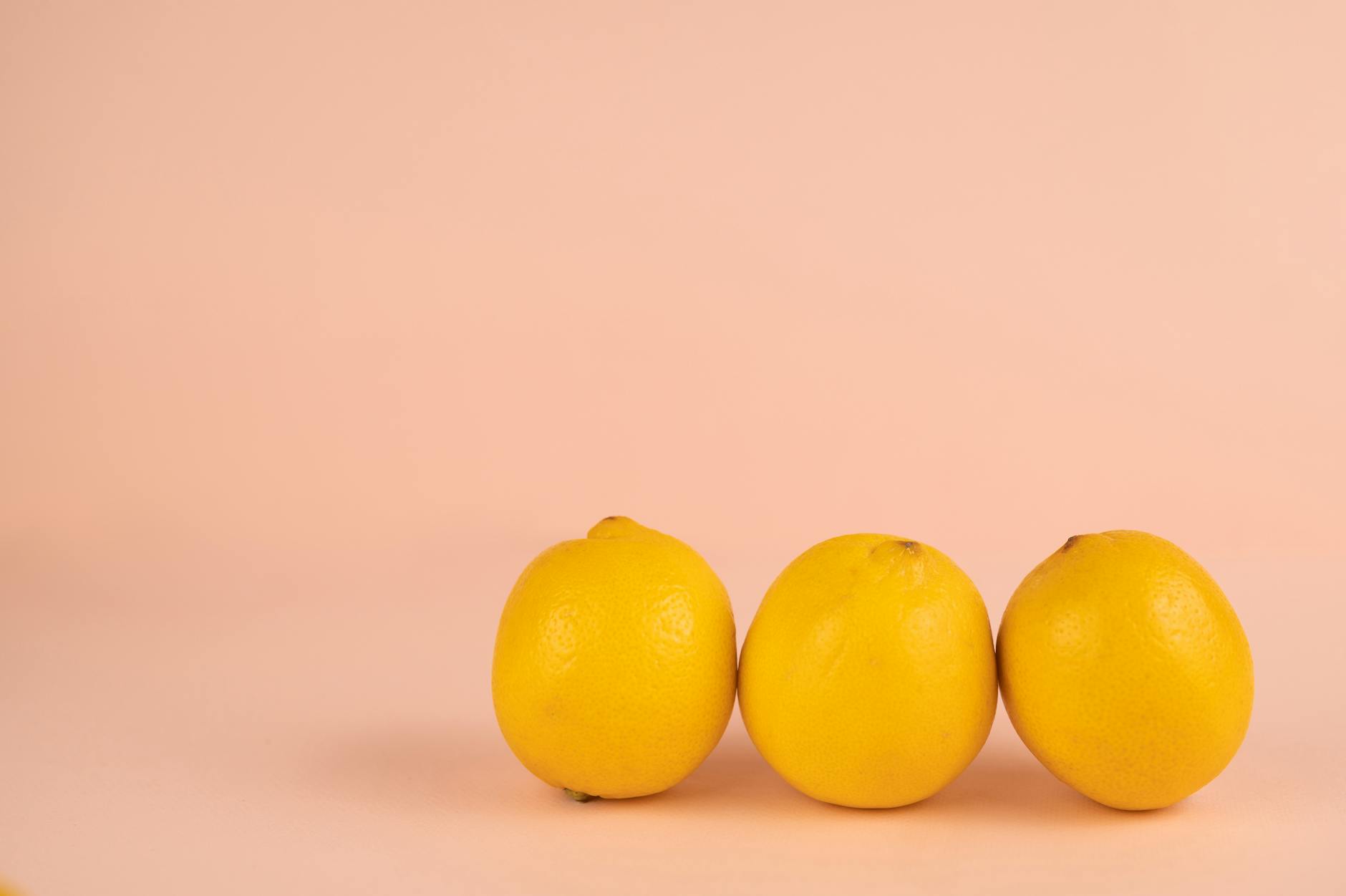 Rangée de citrons frais et lumineux avec leurs pédoncules sur un fond pastel, symbolisant la fraîcheur et la sensibilité